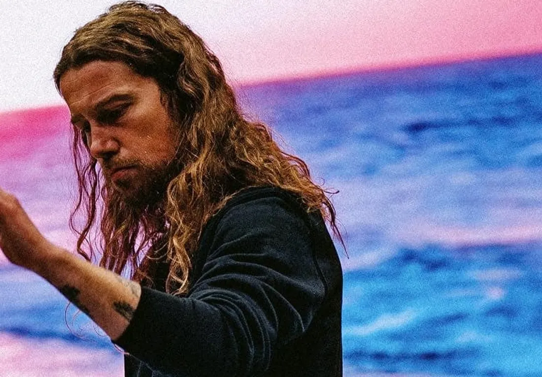 Julien Doré se tient devant un arrière-plan coloré