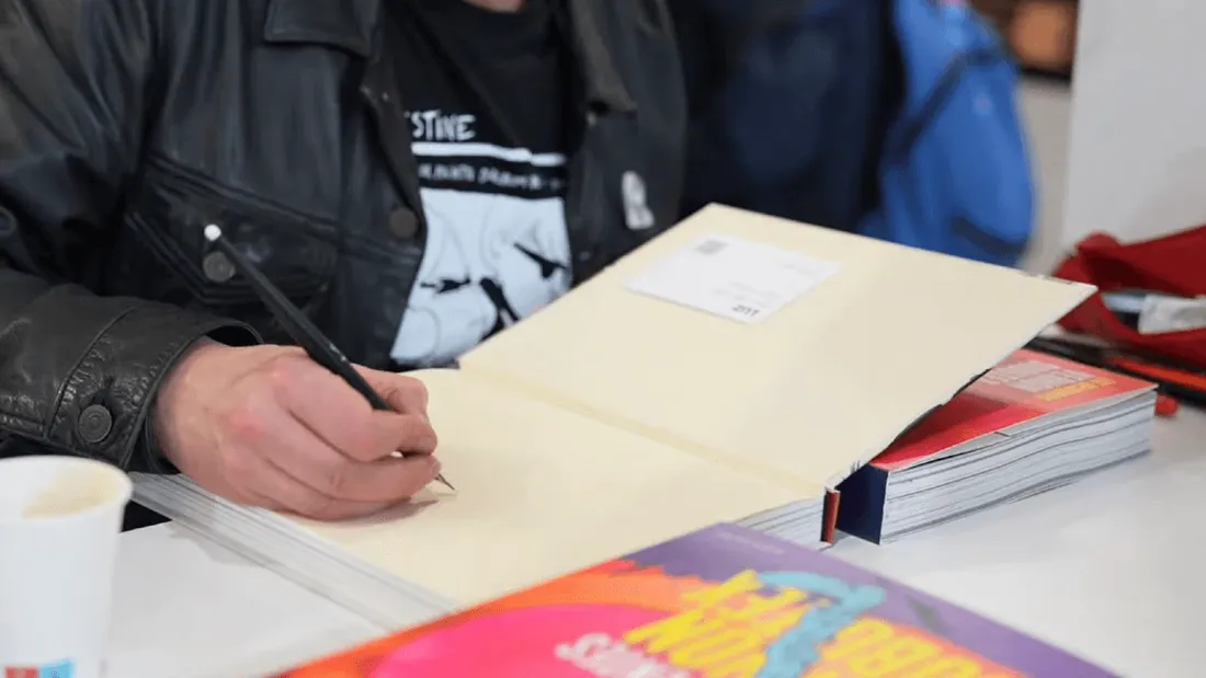 Un auteur signe une dédicace au Festival de la BD Angoulême en 2025
