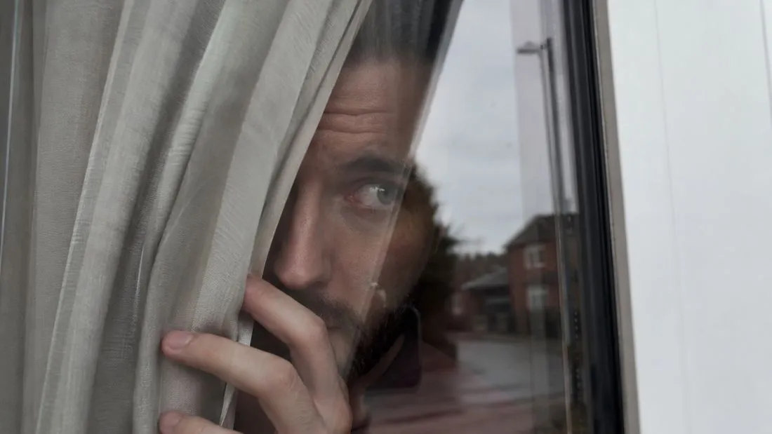 Homme qui regarde par la fenêtre de son logement