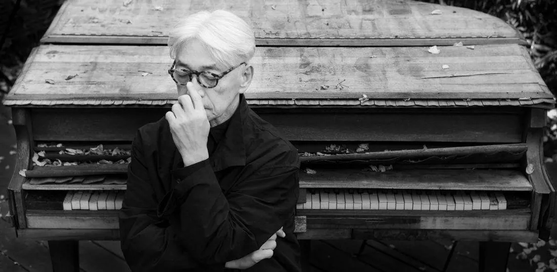 Bildunterschrift auf Deutsch: Ryuichi Sakamoto vor einem vom Tsunami beschädigten Klavier.