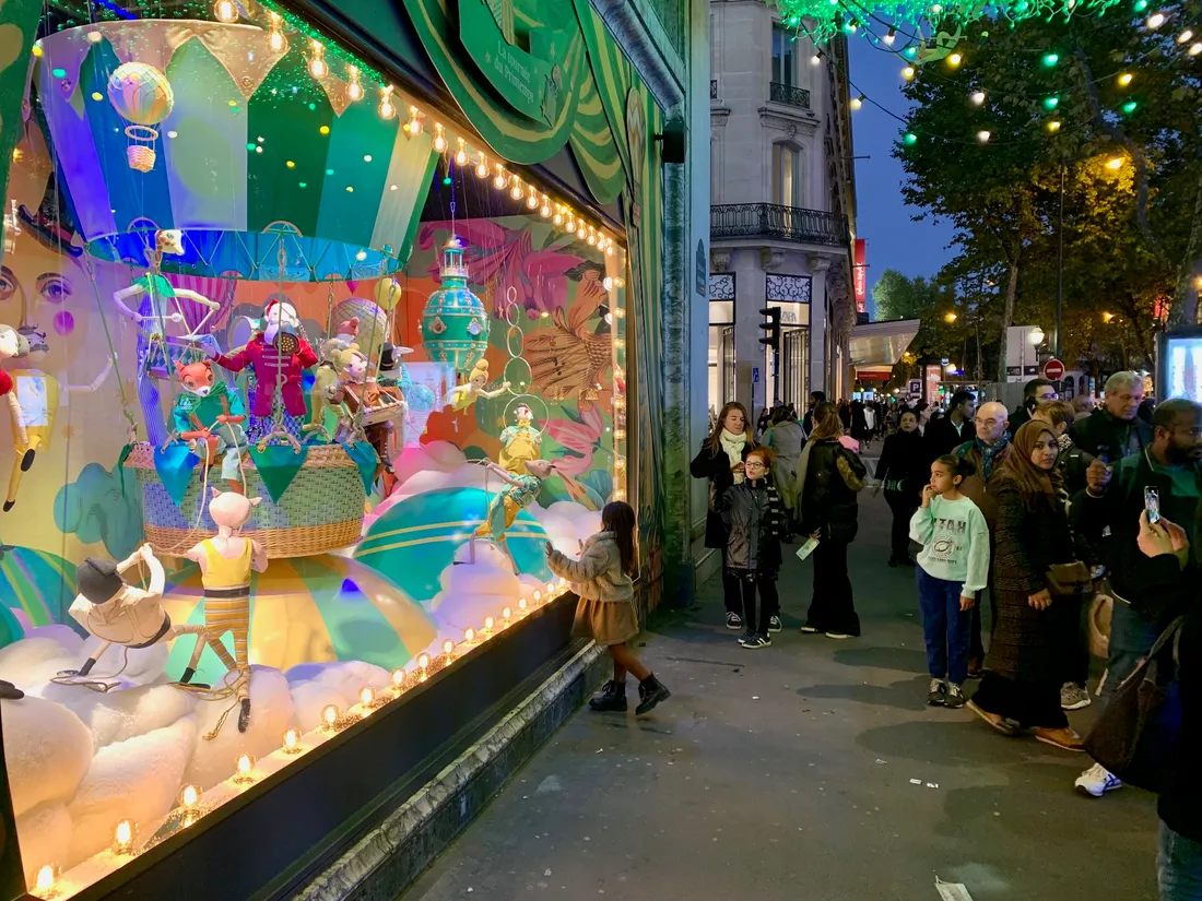 Une petite fille s'approche pour regarder les détails des vitrines situées boulevard Haussmann.