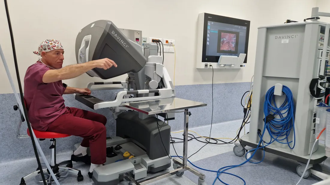 Le docteur Amara derrière le robot qui l'assiste pendant toute l'opération