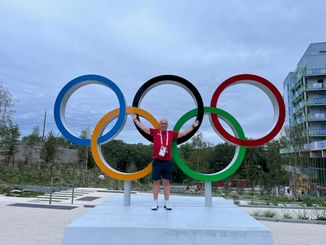 François Meston devant les anneaux dans le village olympique