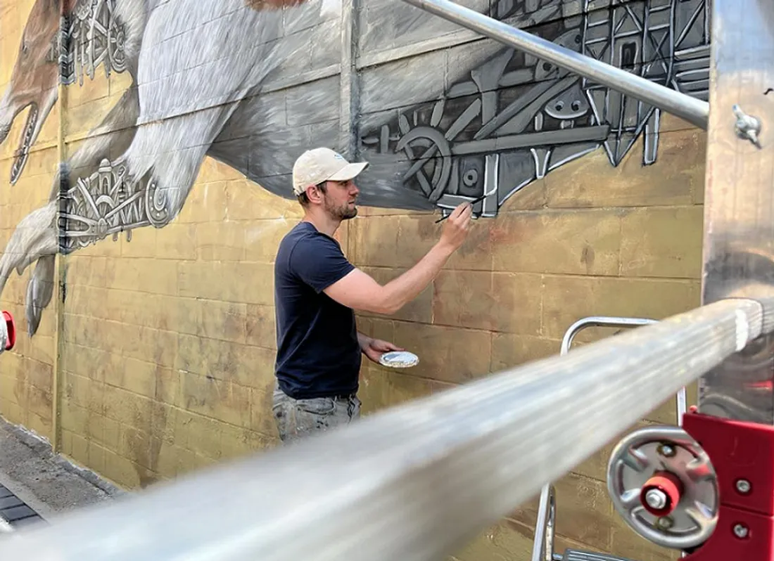 Ardif, l'artiste, en pleine réalisation de sa fresque le long de la rue Voltaire, au Mans