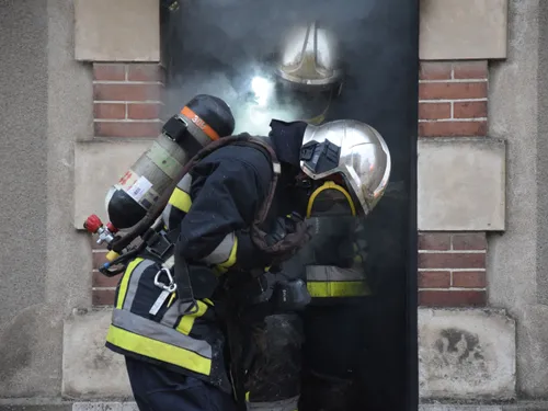 De la fumée s'échappe de la toiture d'un pavillon